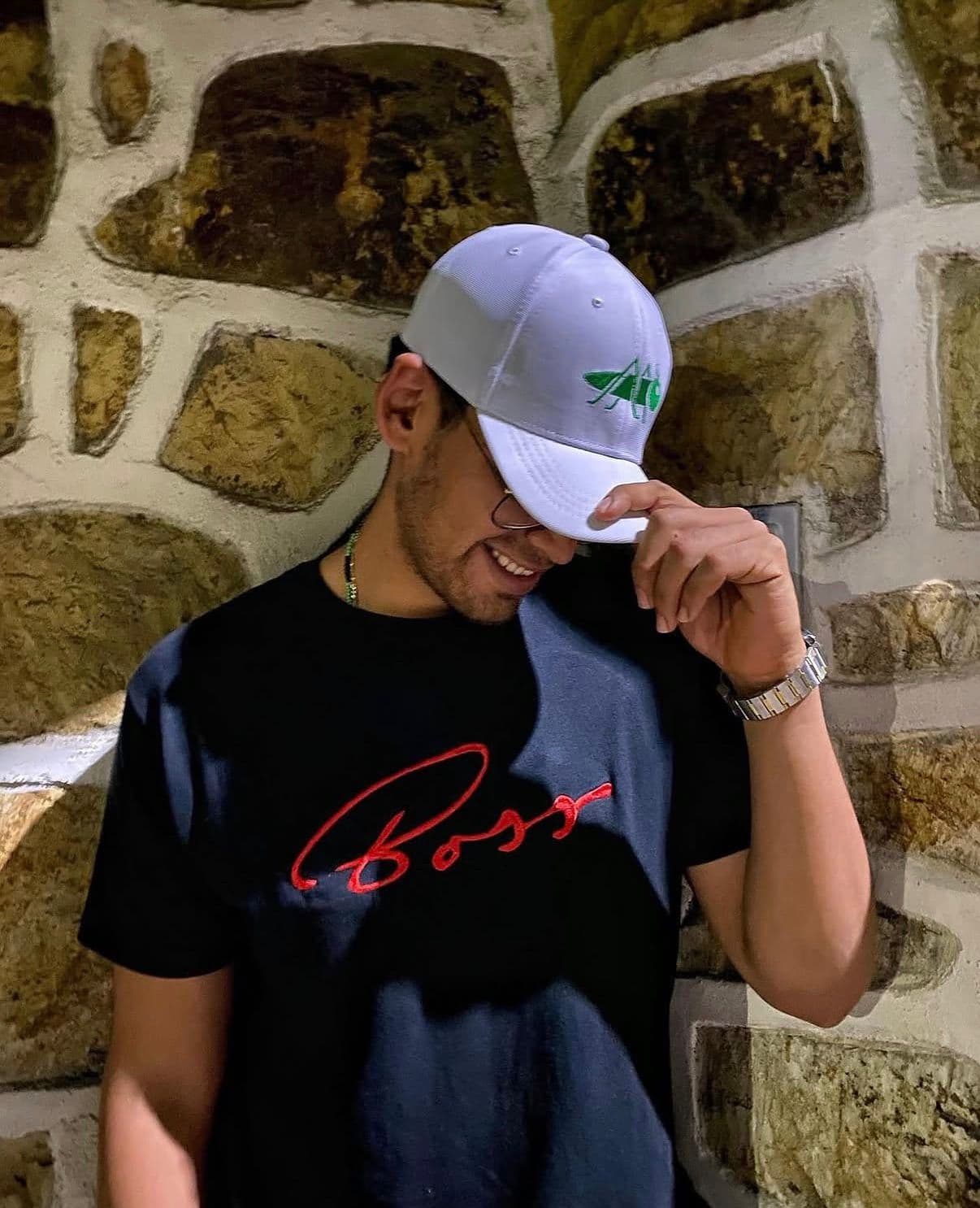 Modelo usando una gorra bordada junto a un muro de piedra